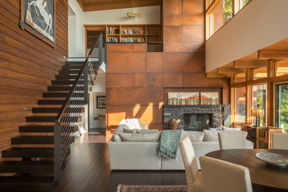 Cette image montre un grand salon design en bois ouvert avec une salle de réception, un mur marron, une cheminée standard, un manteau de cheminée en pierre, un sol marron, aucun téléviseur, un plafond en bois et un escalier.