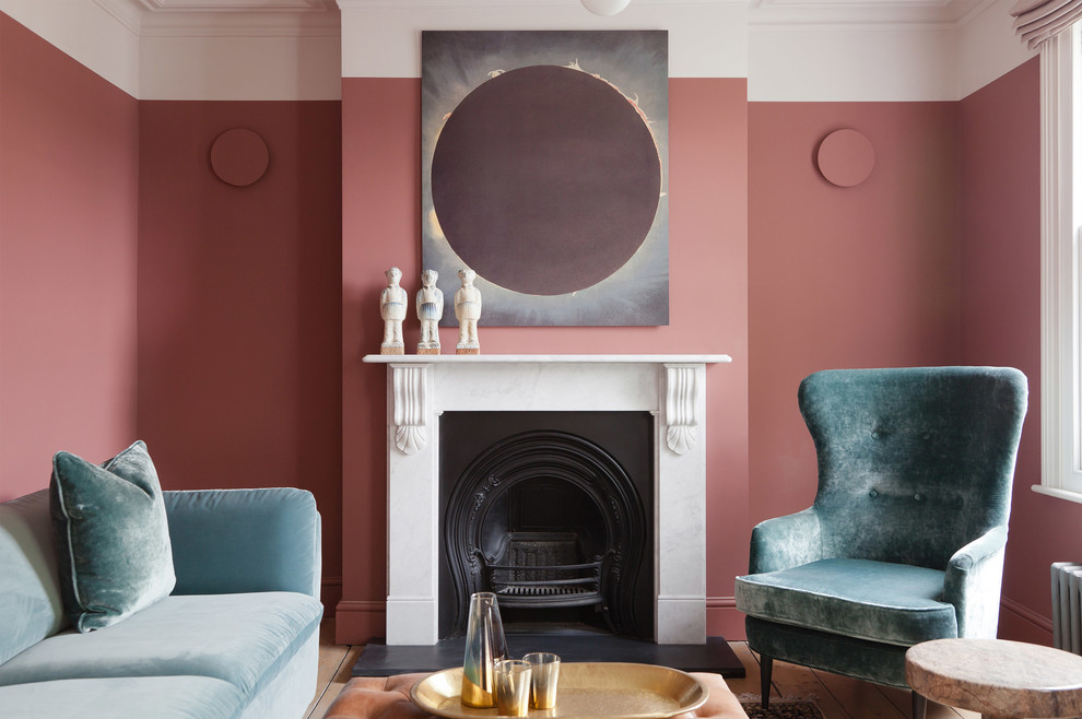 Example of a small trendy enclosed light wood floor and beige floor living room design in London with pink walls and a standard fireplace