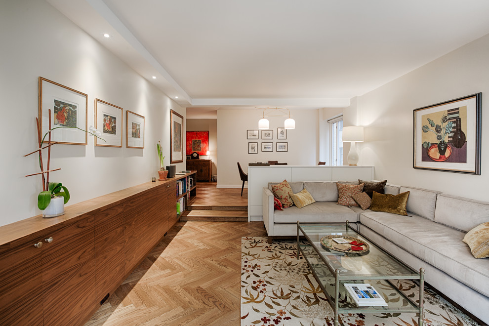 Réalisation d'un salon design ouvert avec une salle de réception, un mur beige, un sol en bois brun, un téléviseur dissimulé et un sol marron.