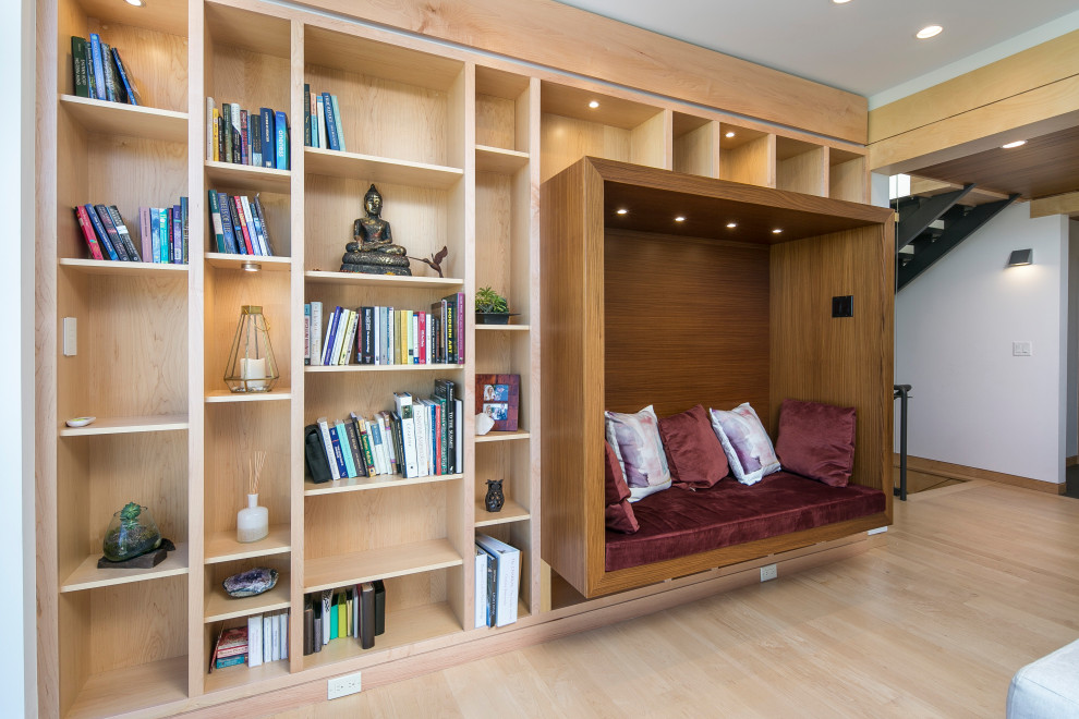 Modelo de biblioteca en casa contemporánea pequeña sin televisor con paredes blancas, suelo de madera clara y suelo beige