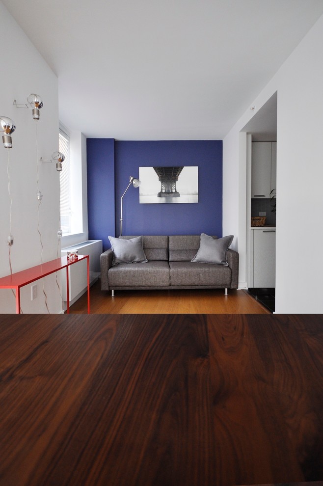 Стильный дизайн: открытая гостиная комната среднего размера в стиле модернизм с белыми стенами, телевизором на стене и светлым паркетным полом - последний тренд