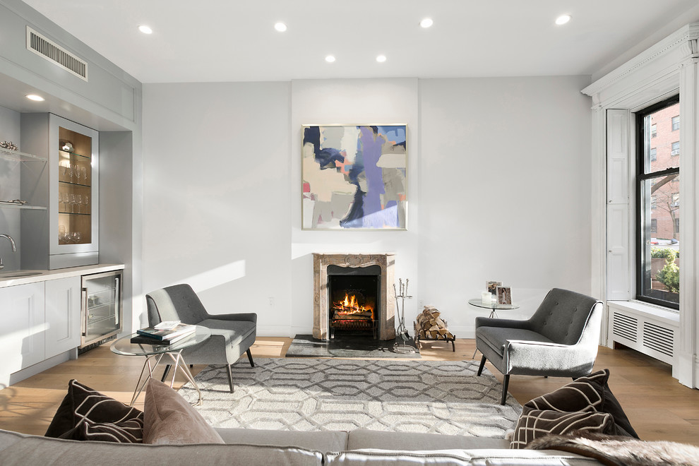 Fernseherloses Klassisches Wohnzimmer mit grauer Wandfarbe, hellem Holzboden, Kamin und Kaminumrandung aus Stein in New York