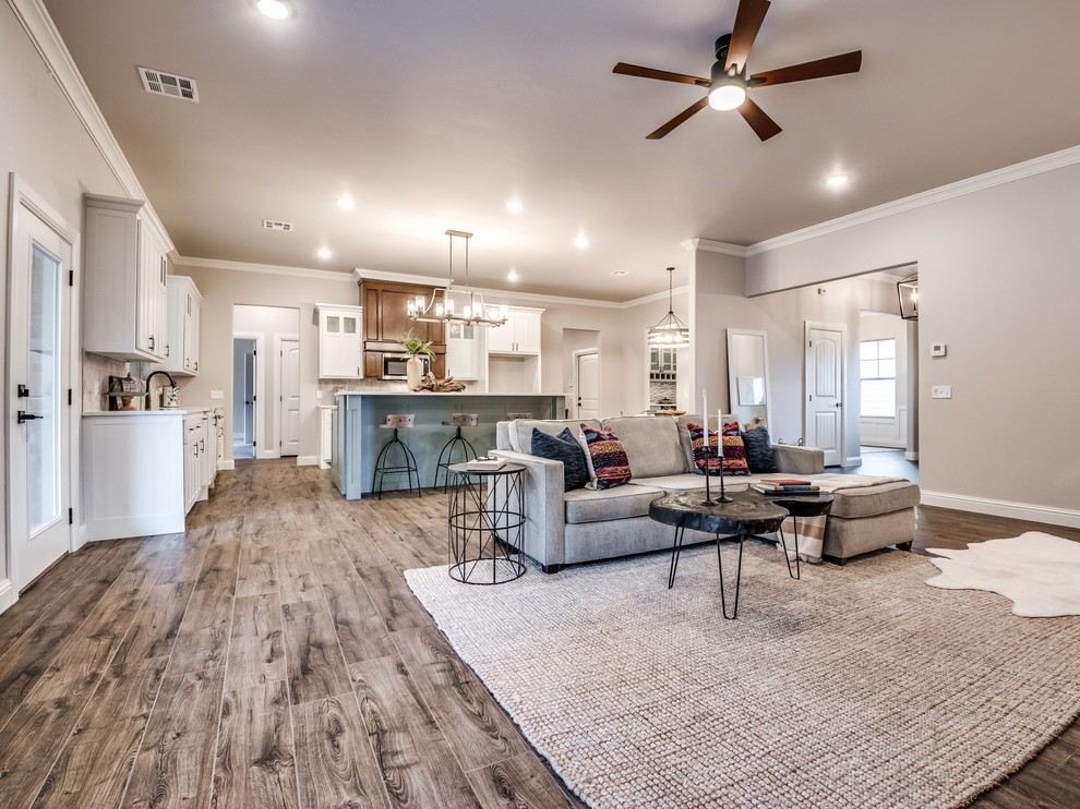 Expansive farmhouse open plan living room in Oklahoma City with beige walls, light hardwood flooring, a standard fireplace and a brick fireplace surround.