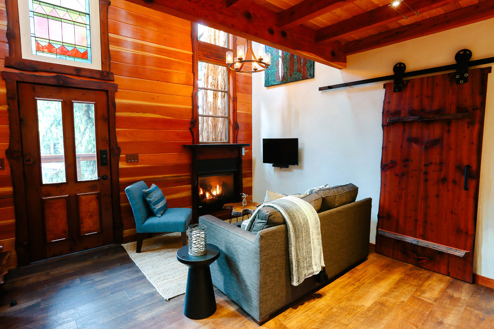 Bild på ett litet rustikt loftrum, med vita väggar, vinylgolv, en standard öppen spis, en spiselkrans i trä och en väggmonterad TV