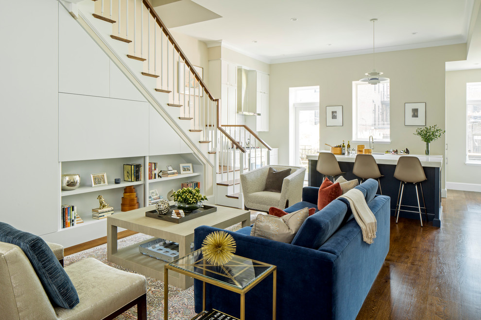 This is an example of a mid-sized transitional open concept living room in Boston with beige walls, medium hardwood floors, a concealed tv and brown floor.