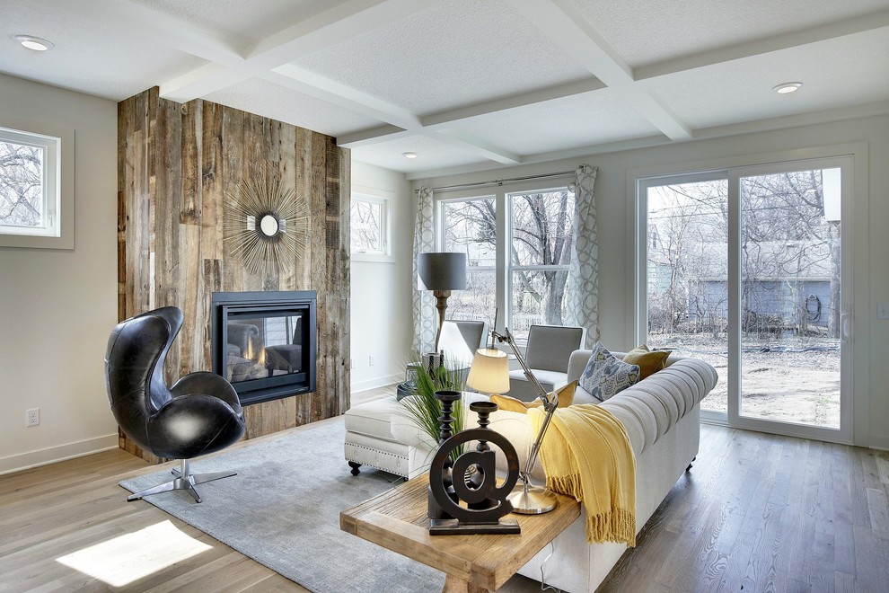This is an example of a large country open plan living room in Minneapolis with white walls, light hardwood flooring, a standard fireplace, a wooden fireplace surround and a wall mounted tv.