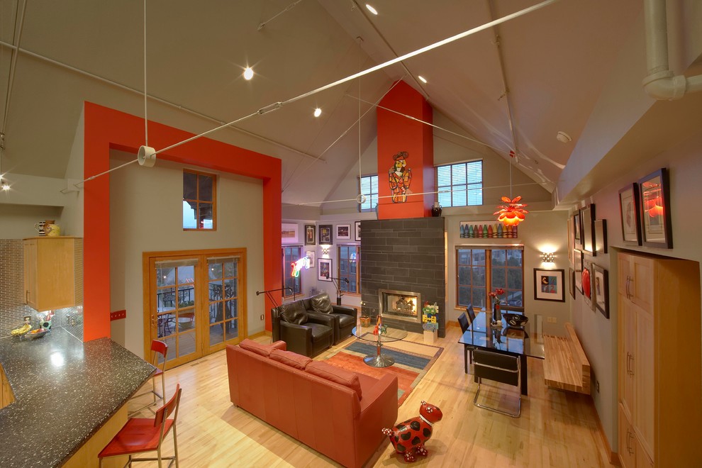 На фото: двухуровневая гостиная комната в современном стиле с красными стенами, светлым паркетным полом, стандартным камином, фасадом камина из камня и скрытым телевизором