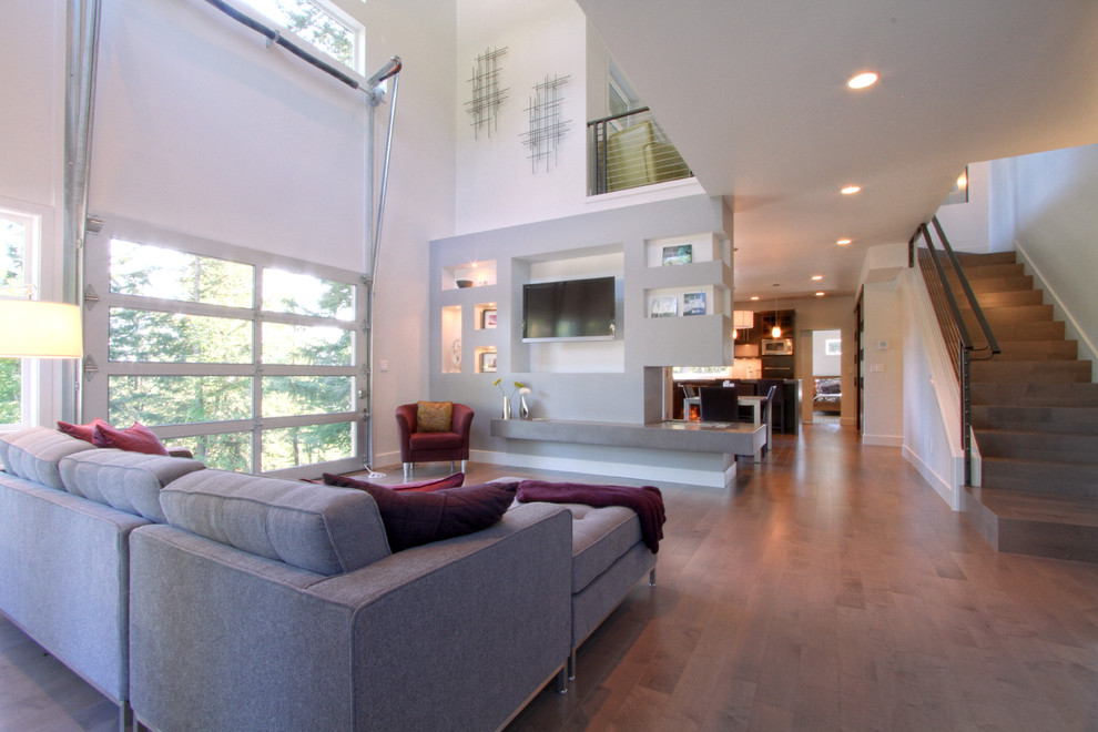 Immagine di un soggiorno moderno di medie dimensioni e aperto con pareti grigie, pavimento in legno massello medio e parete attrezzata