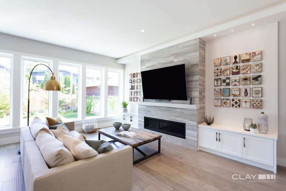 Large traditional formal open plan living room in Vancouver with grey walls, light hardwood flooring, a ribbon fireplace, a tiled fireplace surround and a wall mounted tv.