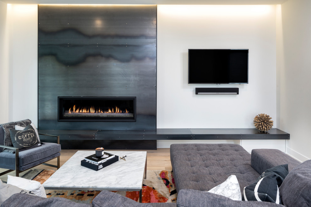 ミネアポリスにある高級な中くらいなインダストリアルスタイルのおしゃれなLDK (白い壁、淡色無垢フローリング、横長型暖炉、金属の暖炉まわり、壁掛け型テレビ) の写真