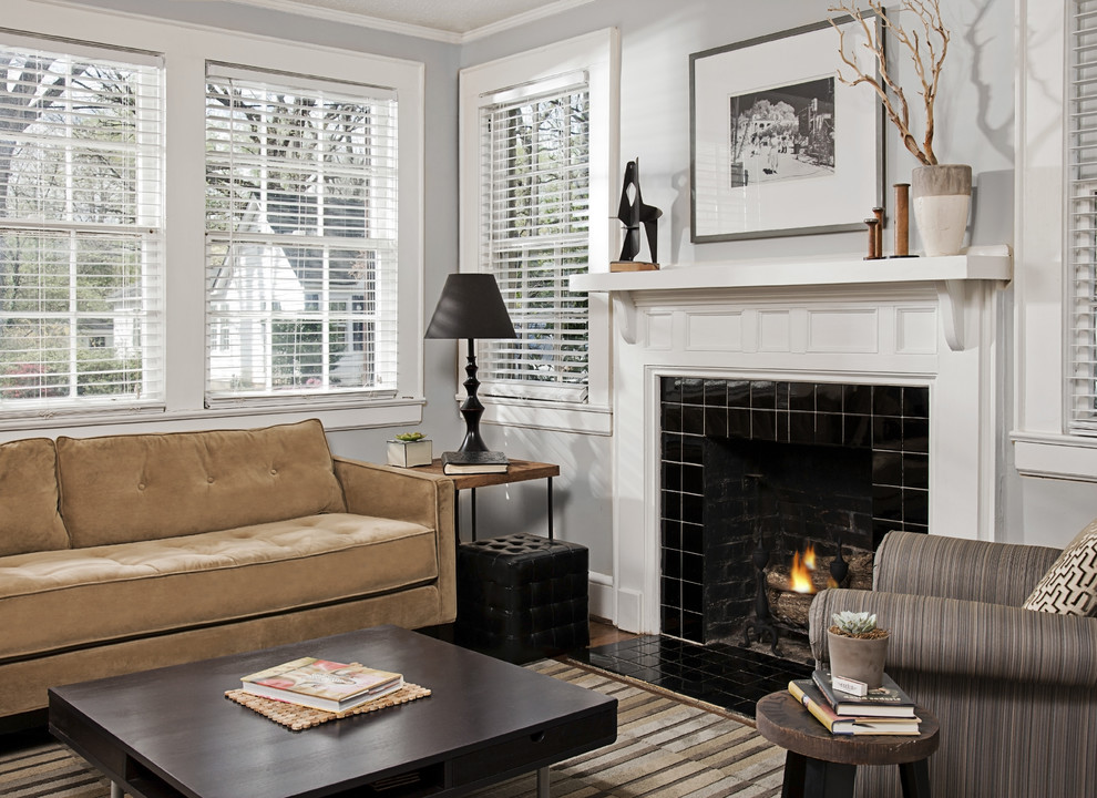 На фото: изолированная гостиная комната в стиле фьюжн с серыми стенами, стандартным камином и фасадом камина из плитки без телевизора
