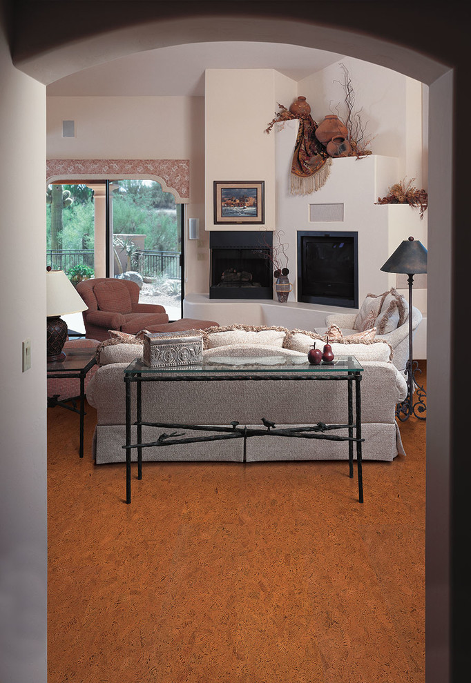 Exemple d'un salon sud-ouest américain de taille moyenne avec un mur blanc, un sol en liège, une cheminée d'angle, un manteau de cheminée en plâtre et un téléviseur encastré.