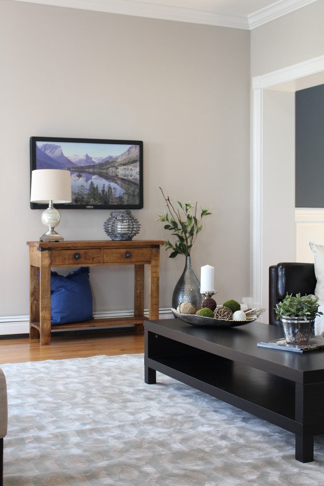 Modelo de salón cerrado tradicional renovado grande con paredes grises, suelo de madera en tonos medios y televisor colgado en la pared