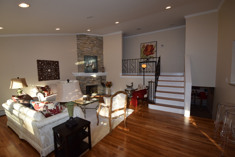 Mittelgroßes, Fernseherloses, Offenes Klassisches Wohnzimmer mit beiger Wandfarbe, braunem Holzboden, Eckkamin und Kaminumrandung aus Stein in New York