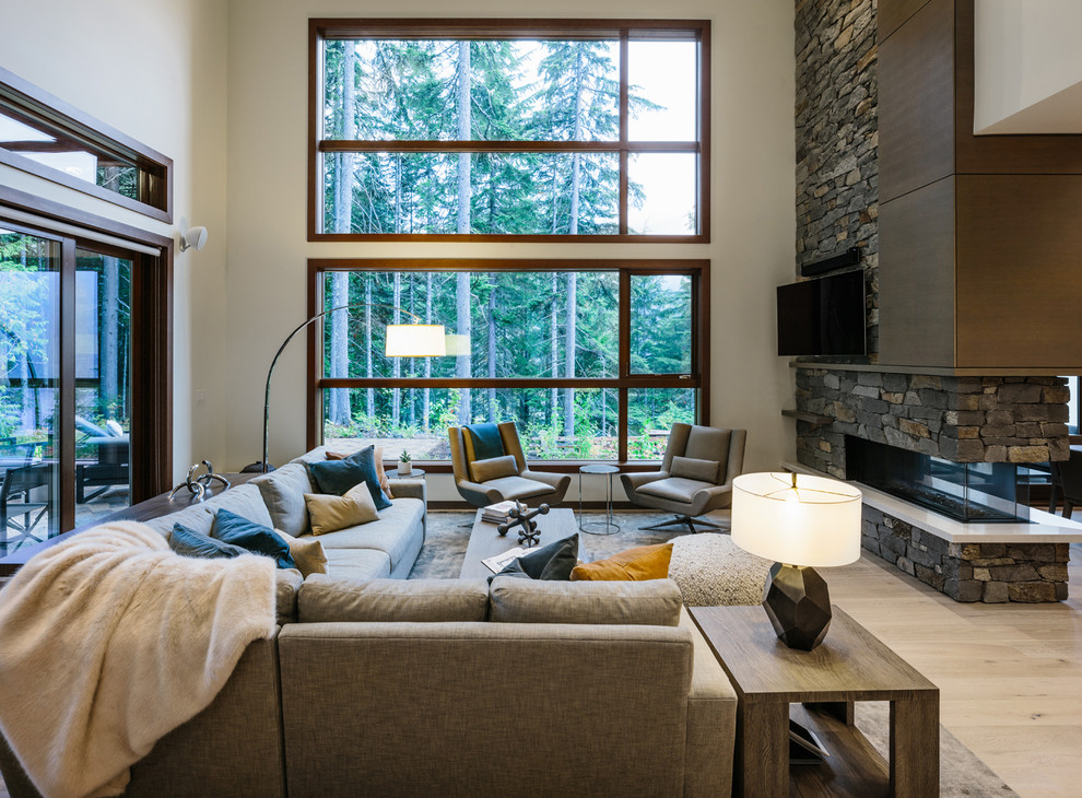 Großes, Offenes Modernes Wohnzimmer mit weißer Wandfarbe, braunem Holzboden, Kamin, Kaminumrandung aus Stein, TV-Wand und grauem Boden in Vancouver