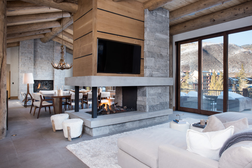 This is an example of a medium sized contemporary formal open plan living room in Denver with white walls, concrete flooring, a two-sided fireplace, a stone fireplace surround, a wall mounted tv and grey floors.