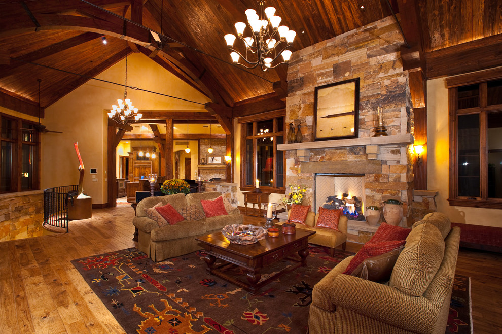 Photo of a large rustic formal open plan living room in Denver with beige walls, medium hardwood flooring, a standard fireplace, a stone fireplace surround, no tv, brown floors and a vaulted ceiling.