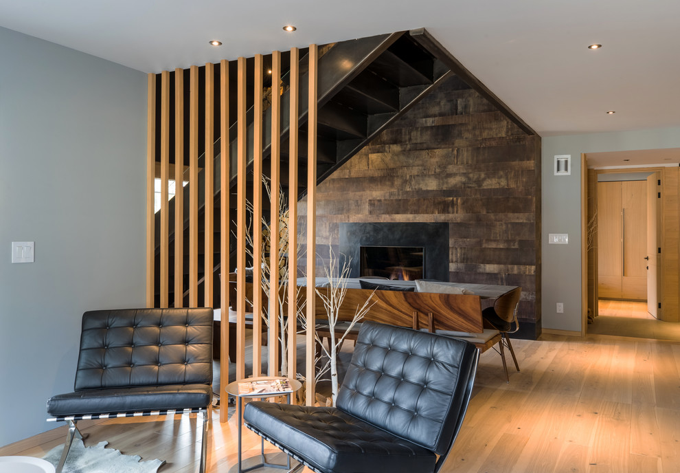 Diseño de salón gris y abierto minimalista de tamaño medio sin televisor con paredes grises, suelo de madera clara, suelo marrón, todas las chimeneas y marco de chimenea de madera
