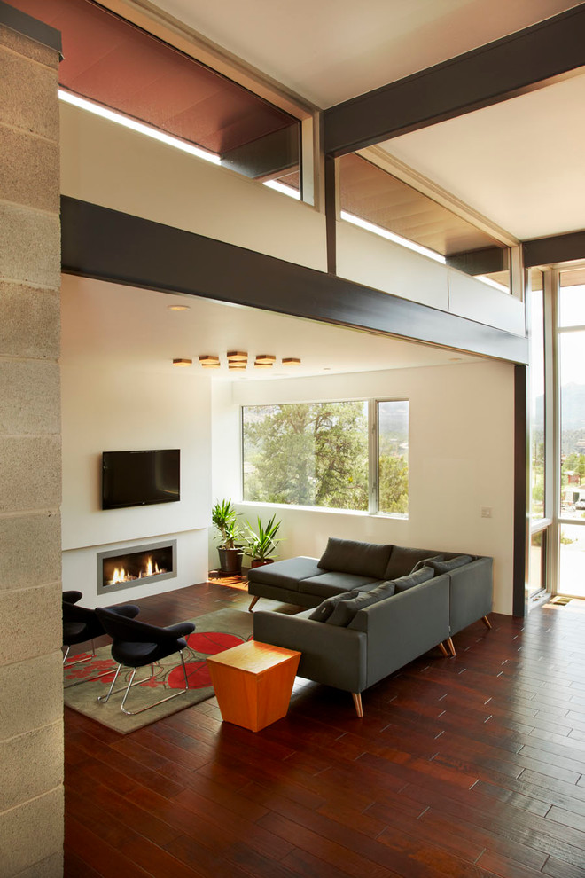 Идея дизайна: открытая гостиная комната среднего размера в стиле модернизм с белыми стенами, паркетным полом среднего тона, горизонтальным камином, фасадом камина из штукатурки, телевизором на стене и красным полом