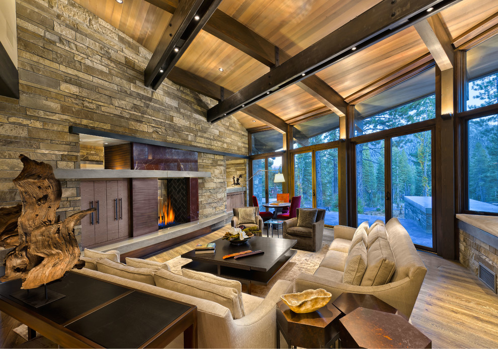 Exemple d'un très grand salon montagne ouvert avec un sol en bois brun, une cheminée double-face, un manteau de cheminée en métal, une salle de réception et aucun téléviseur.