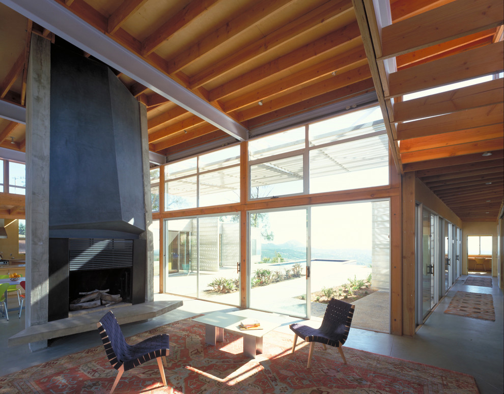 Großes, Offenes Modernes Wohnzimmer mit Kamin, Betonboden, Kaminumrandung aus Beton und grauem Boden in Sonstige
