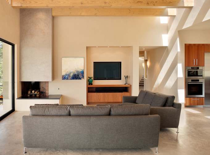 アルバカーキにある高級な広いサンタフェスタイルのおしゃれなLDK (ベージュの壁、コンクリートの床、コーナー設置型暖炉、レンガの暖炉まわり、壁掛け型テレビ) の写真