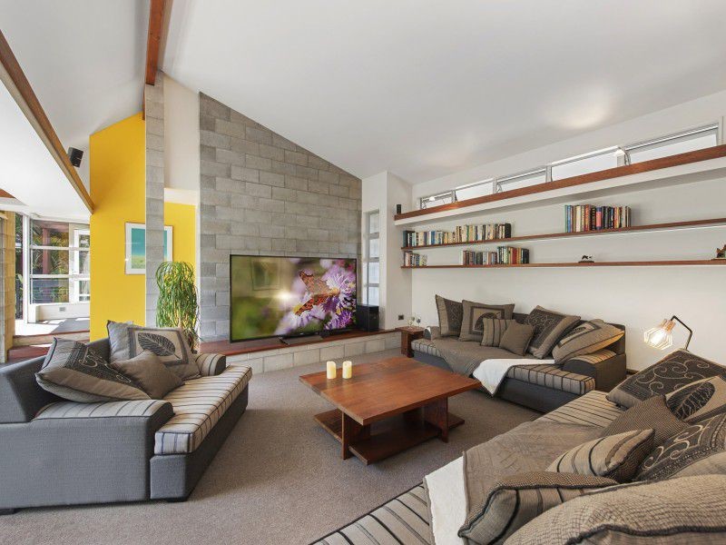 他の地域にあるお手頃価格の中くらいなミッドセンチュリースタイルのおしゃれなリビング (黄色い壁、カーペット敷き、据え置き型テレビ、ベージュの床) の写真
