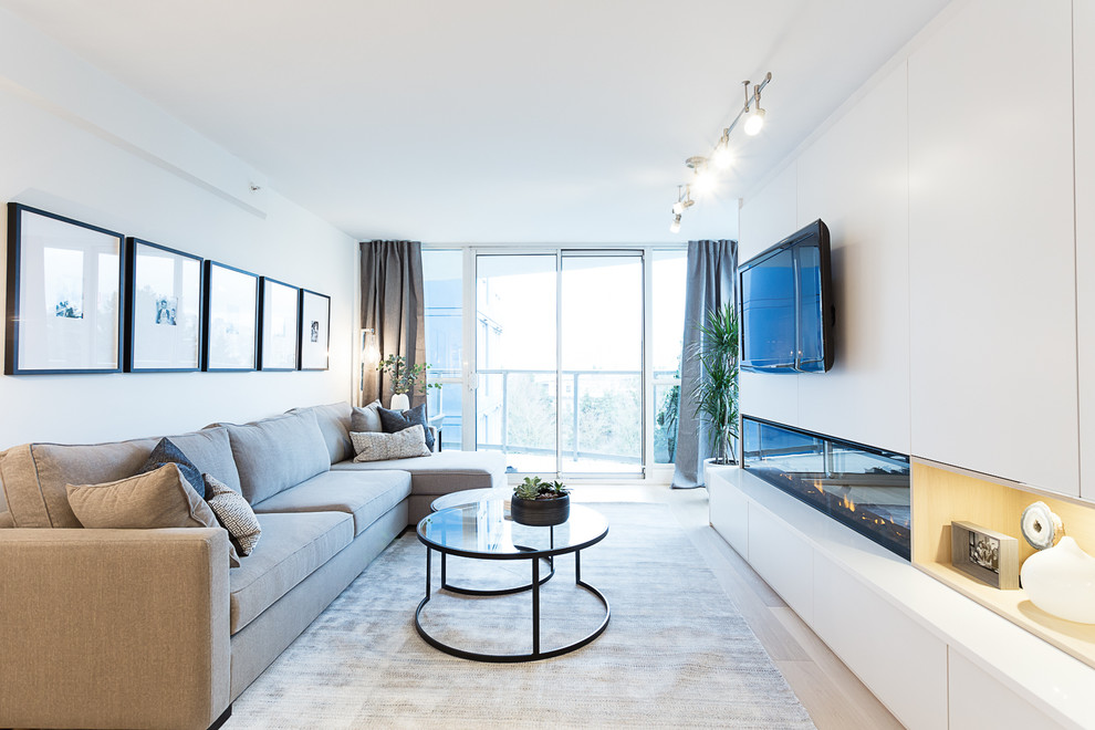 Mittelgroßes, Offenes Modernes Wohnzimmer mit weißer Wandfarbe, hellem Holzboden, Gaskamin, Kaminumrandung aus Holz, TV-Wand und weißem Boden in Vancouver