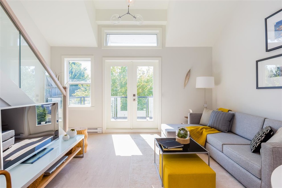 Photo of a scandi living room in Vancouver with grey walls, light hardwood flooring, a freestanding tv and beige floors.