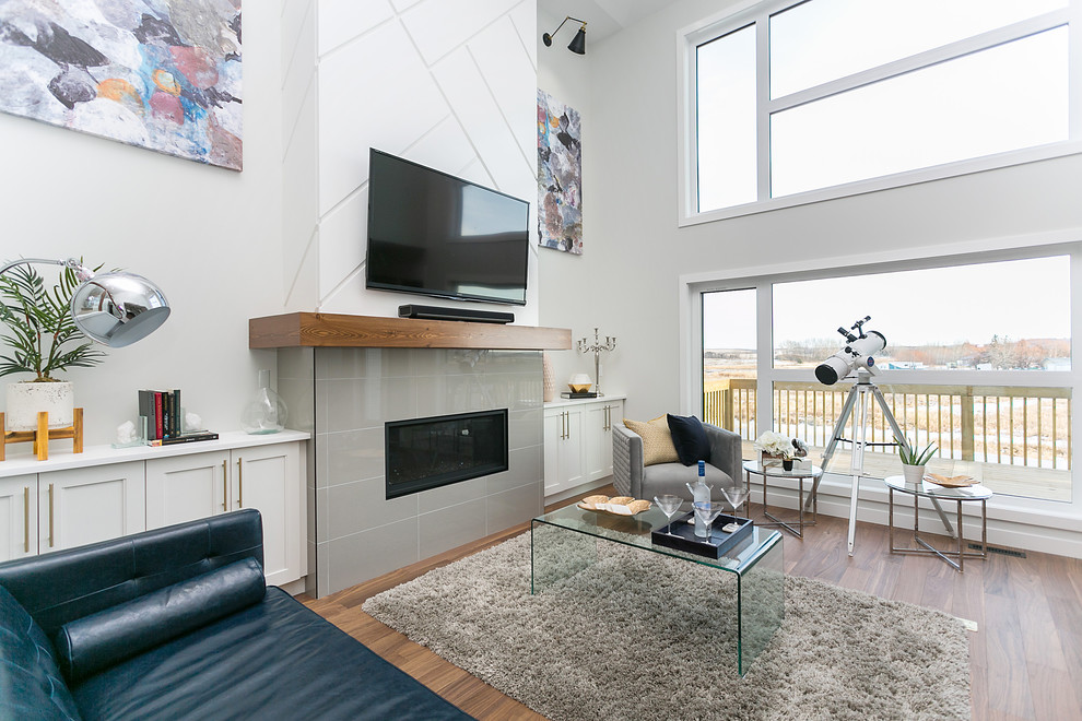 Bild på ett mellanstort funkis allrum med öppen planlösning, med ett finrum, vita väggar, mellanmörkt trägolv, en bred öppen spis, en spiselkrans i trä, en väggmonterad TV och brunt golv