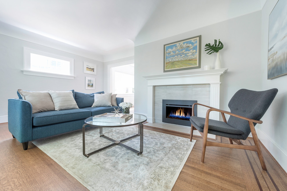 Mittelgroßes, Offenes Klassisches Wohnzimmer mit grauer Wandfarbe, braunem Holzboden, Kamin, Kaminumrandung aus Stein und braunem Boden in Vancouver