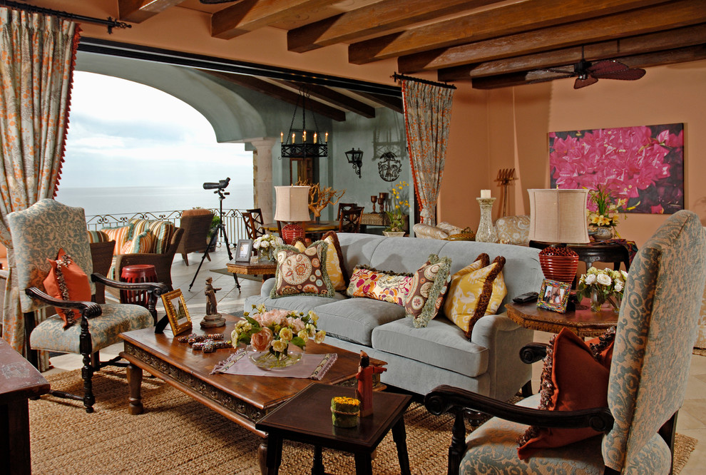 На фото: большая гостиная комната в средиземноморском стиле с оранжевыми стенами и красивыми шторами
