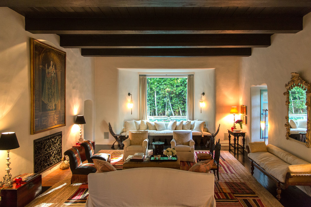 Foto di un grande soggiorno mediterraneo aperto con sala formale, pareti beige, parquet scuro, camino classico e cornice del camino in intonaco