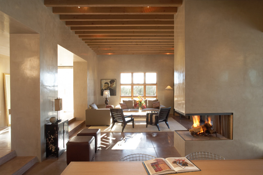 Cette image montre un salon design de taille moyenne et ouvert avec un mur beige, sol en béton ciré, une cheminée standard, un manteau de cheminée en plâtre et aucun téléviseur.