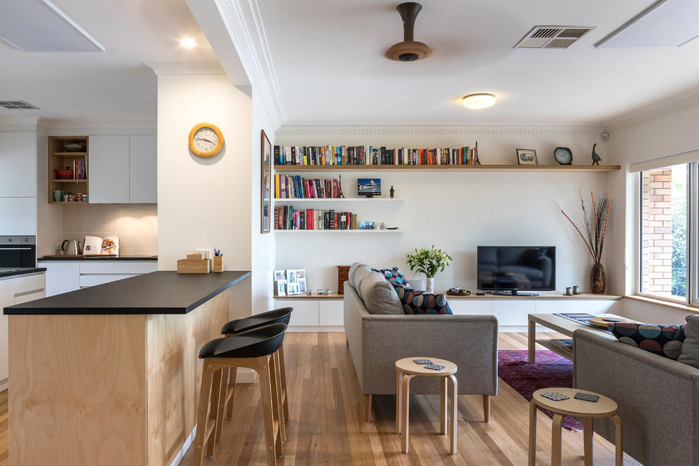 This is an example of a medium sized contemporary open plan living room in Canberra - Queanbeyan with white walls, a freestanding tv, medium hardwood flooring and brown floors.