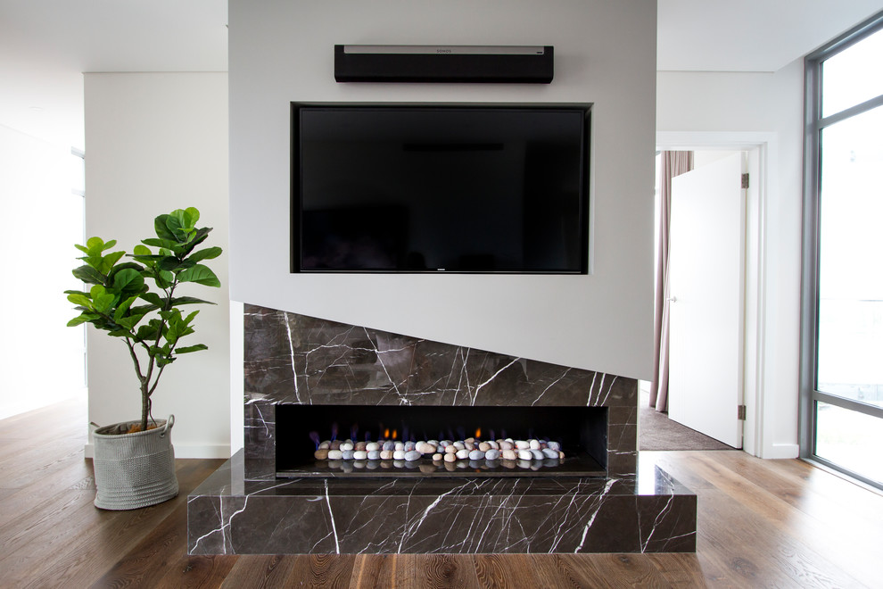シドニーにあるラグジュアリーな巨大なコンテンポラリースタイルのおしゃれなリビング (白い壁、石材の暖炉まわり、茶色い床、濃色無垢フローリング、横長型暖炉、壁掛け型テレビ) の写真
