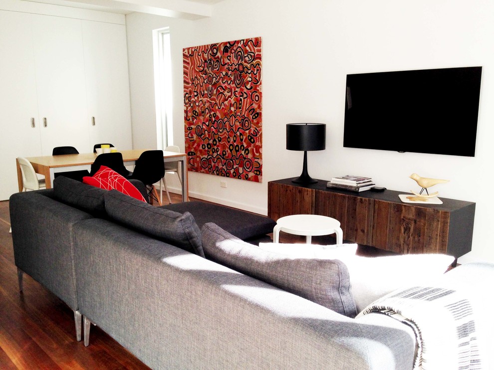 Example of a mid-sized trendy formal and open concept medium tone wood floor living room design in Sydney with white walls and a wall-mounted tv