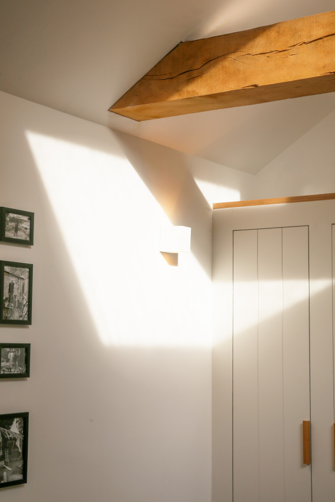Foto de salón abierto nórdico pequeño con paredes blancas, suelo de madera clara, estufa de leña, marco de chimenea de yeso y televisor colgado en la pared