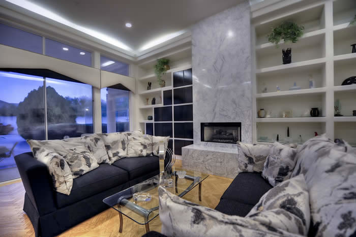 Geräumiges, Repräsentatives, Offenes Modernes Wohnzimmer mit beiger Wandfarbe, braunem Holzboden, Kamin und Kaminumrandung aus Stein in Phoenix