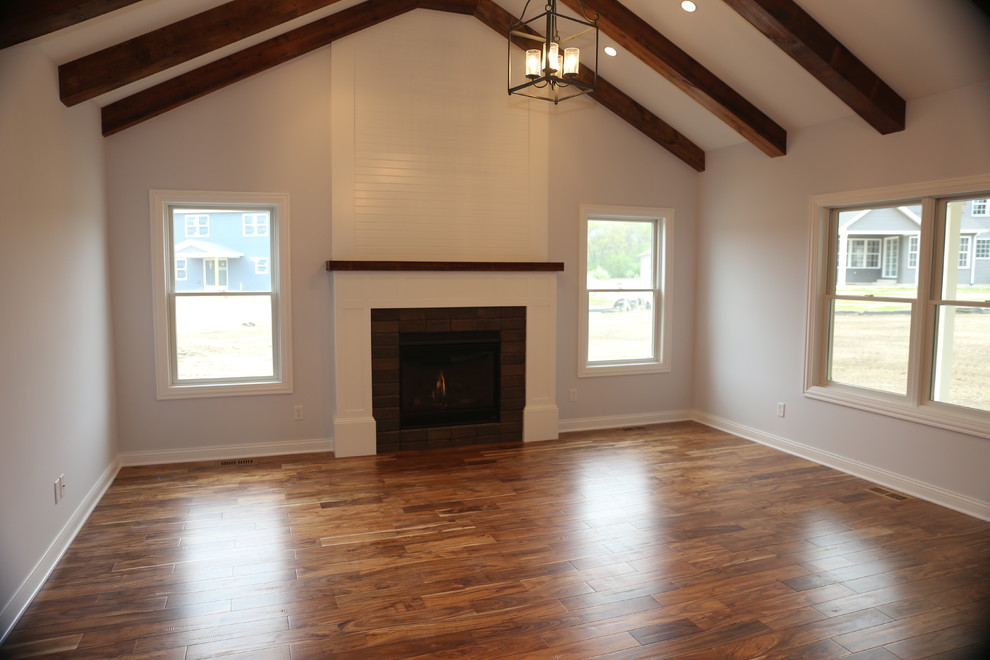 Aménagement d'un grand salon craftsman ouvert avec parquet foncé, une cheminée standard et un manteau de cheminée en brique.