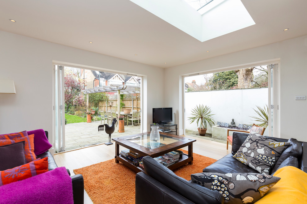 This is an example of a contemporary open plan living room in London with a freestanding tv.