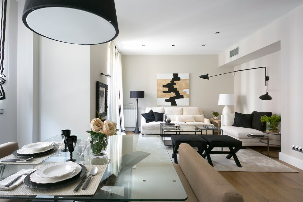 This is an example of a large contemporary formal open plan living room in Madrid with white walls, medium hardwood flooring, no fireplace and no tv.