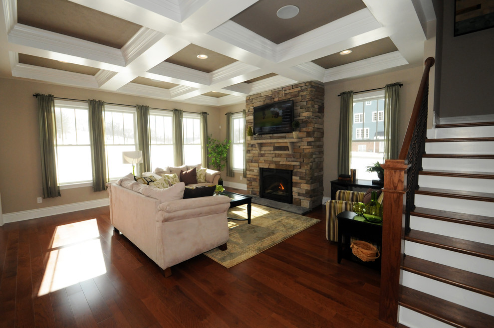 Diseño de salón abierto tradicional renovado con paredes beige, marco de chimenea de piedra y televisor colgado en la pared