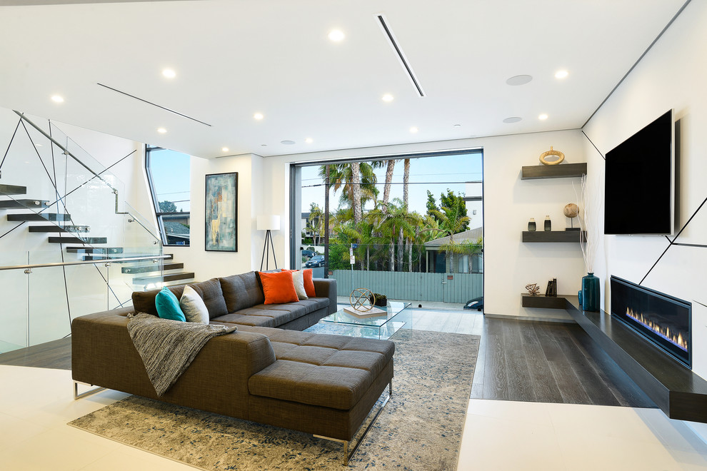 Imagen de salón contemporáneo con paredes blancas, suelo de madera oscura, chimenea lineal y televisor colgado en la pared