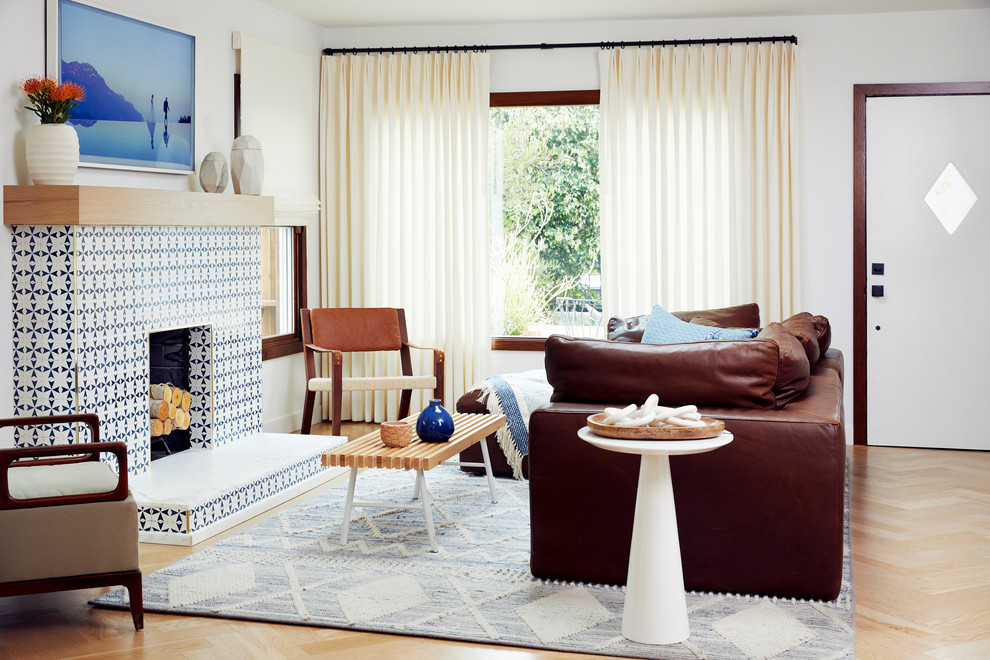Repräsentatives, Fernseherloses, Offenes Modernes Wohnzimmer mit weißer Wandfarbe, braunem Holzboden, Kamin, gefliester Kaminumrandung und braunem Boden in Los Angeles