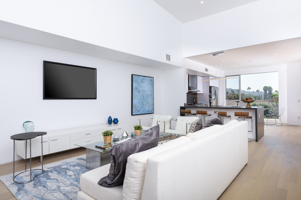 Foto de salón abierto minimalista de tamaño medio con paredes blancas, suelo de madera en tonos medios, televisor colgado en la pared y suelo marrón