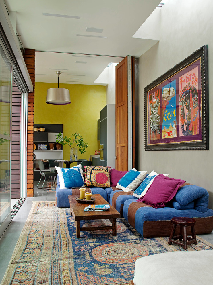 Стильный дизайн: парадная, открытая гостиная комната среднего размера в стиле фьюжн с бетонным полом, серыми стенами и синим диваном без камина, телевизора - последний тренд