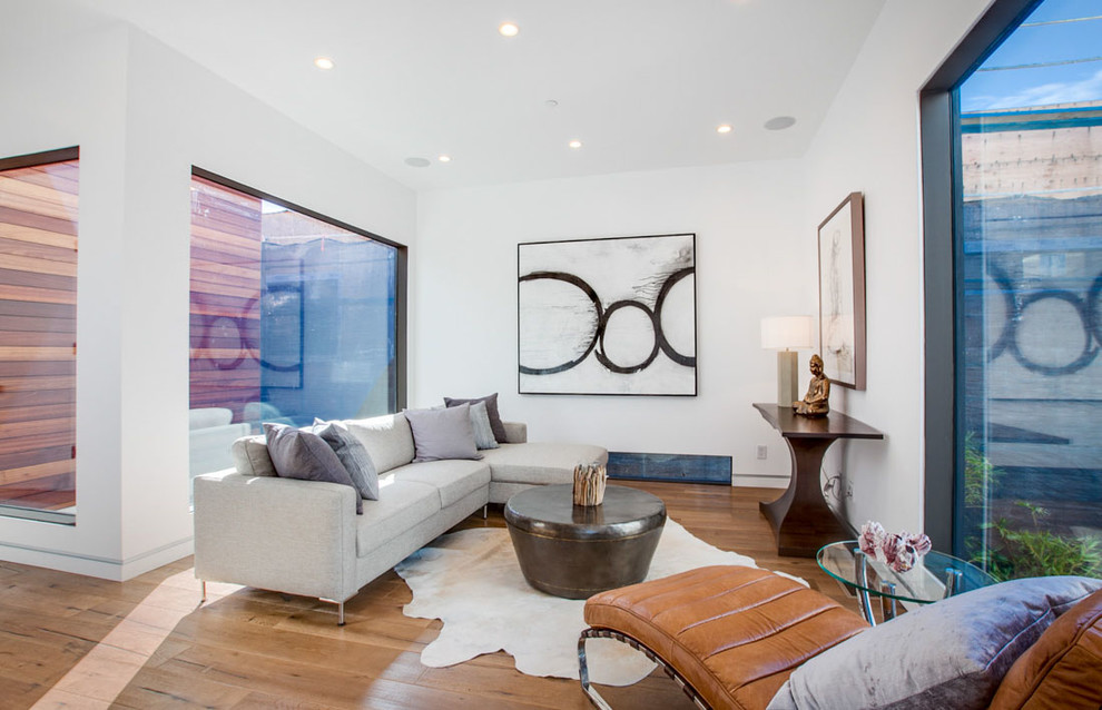 This is an example of a contemporary living room in Los Angeles with white walls and medium hardwood flooring.