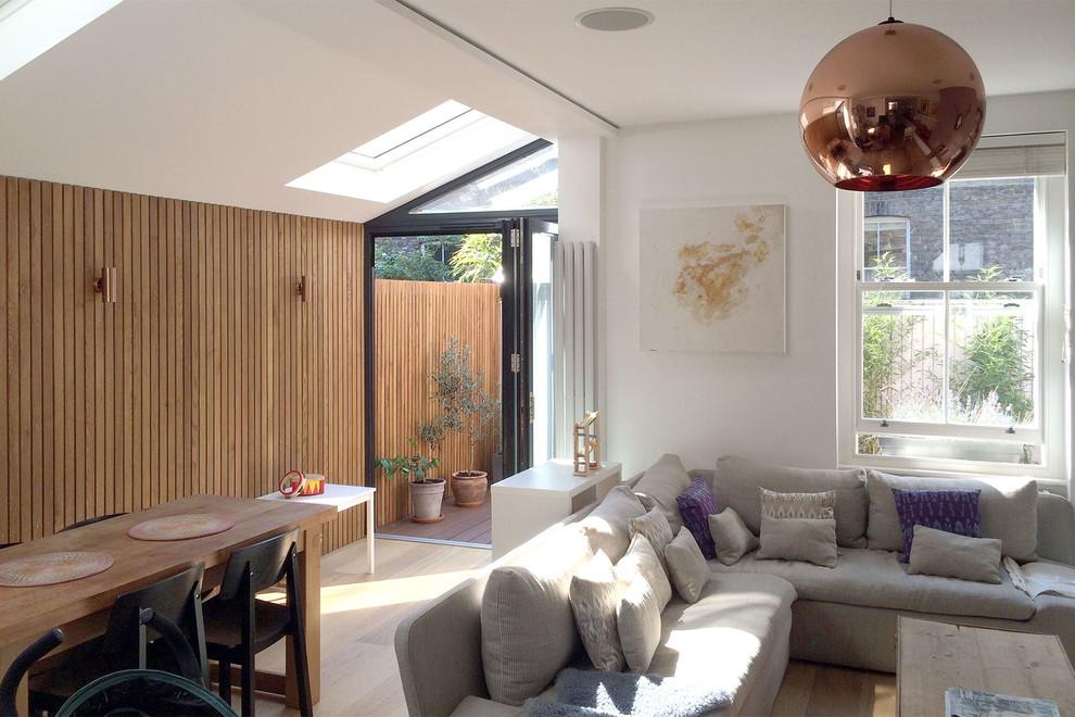 Diseño de salón abierto contemporáneo pequeño con paredes blancas, suelo de madera clara y televisor independiente