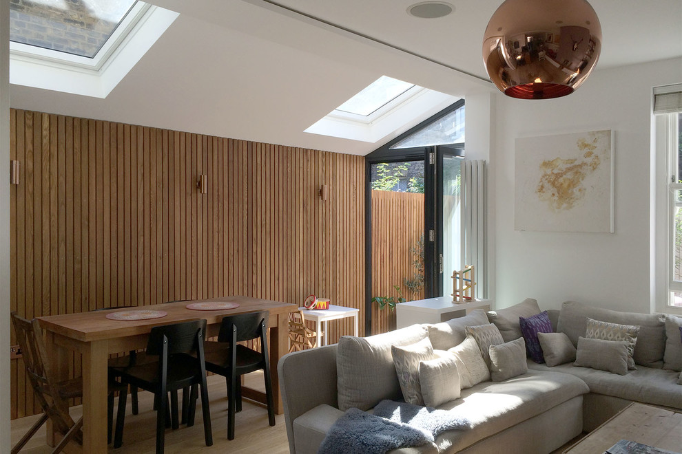 Small contemporary open plan living room in London with white walls, light hardwood flooring and a freestanding tv.